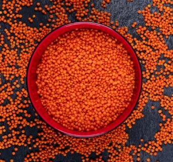 Top view red lentils in red bowl on dark stone background. horizontal